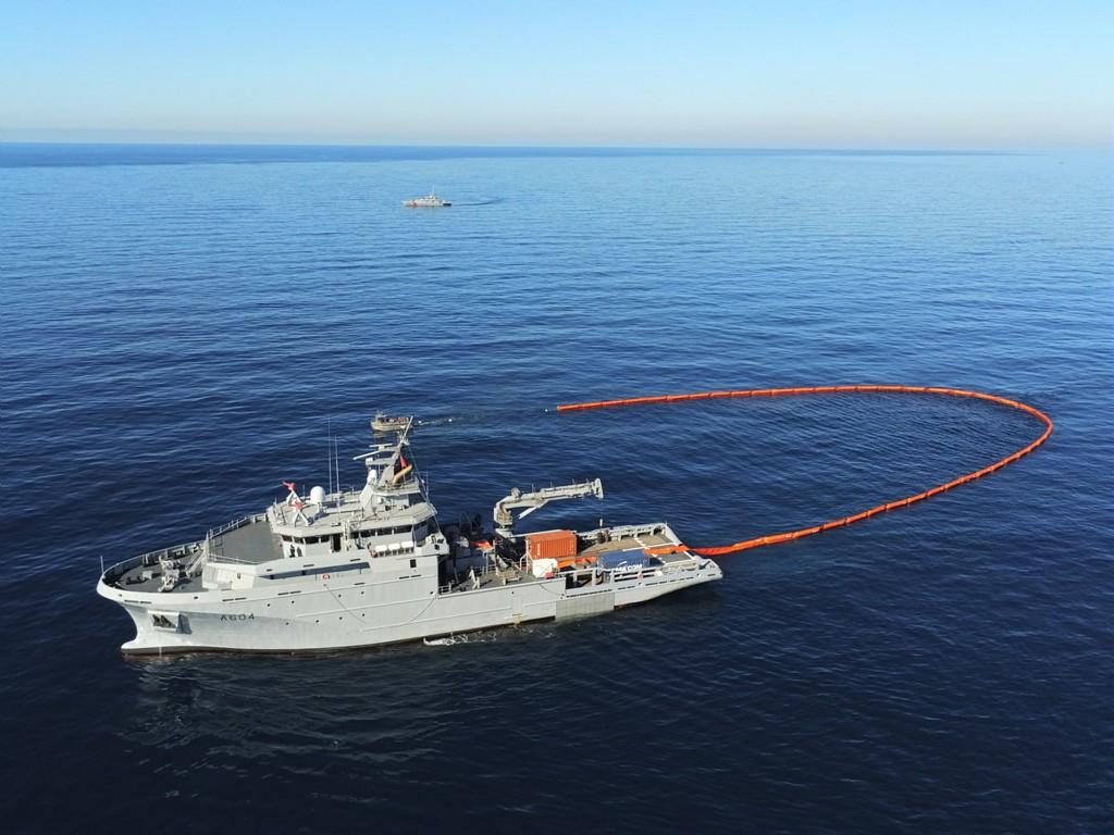 The Warship Seine towing her anti-pollution floating barrier, with assistance of her small workboat